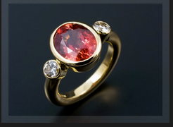 Oval 4.2ct Blood Orange Sapphire with 2 x 0.20ct F VS Round Brilliants in 18kt Yellow Gold Rub Over Setting